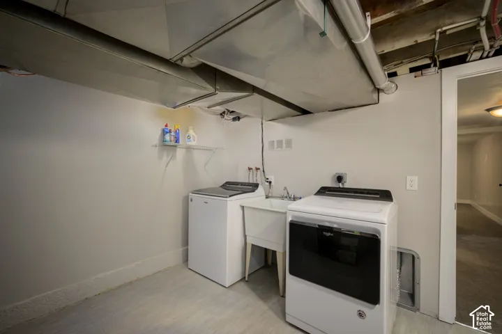 Utility area featuring a utility sink, light gray walls, and light-toned flooring