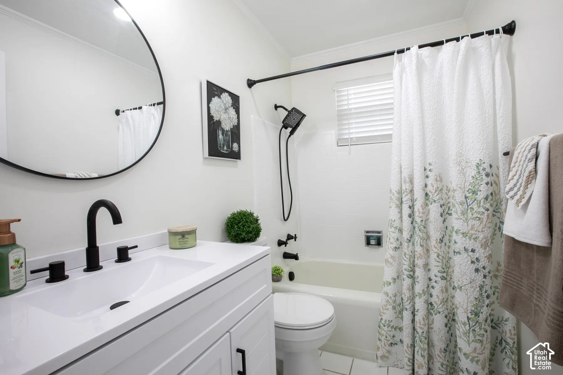 White vanity with integrated sink, matte black faucet, and round framed mirror