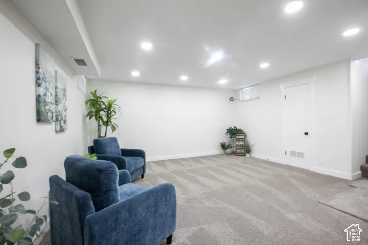 Recessed lighting illuminates the carpeted flooring and white walls