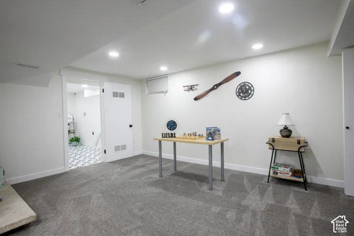 Recessed ceiling lighting, durable carpet flooring, a paneled accent wall, and a white interior door with louvered panels
