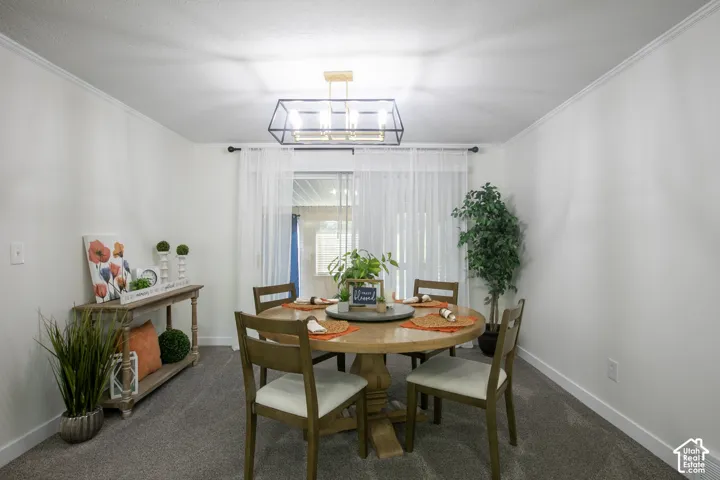 Recessed lighting, crown molding, modern black and gold chandelier, light gray carpeting, and a sliding glass door