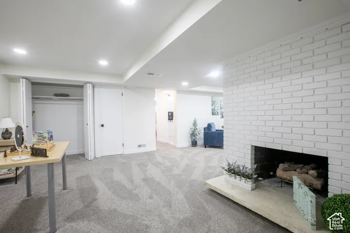 Recessed lighting, white painted brick fireplace, carpet flooring, bi-fold closet doors, and solid panel interior doors