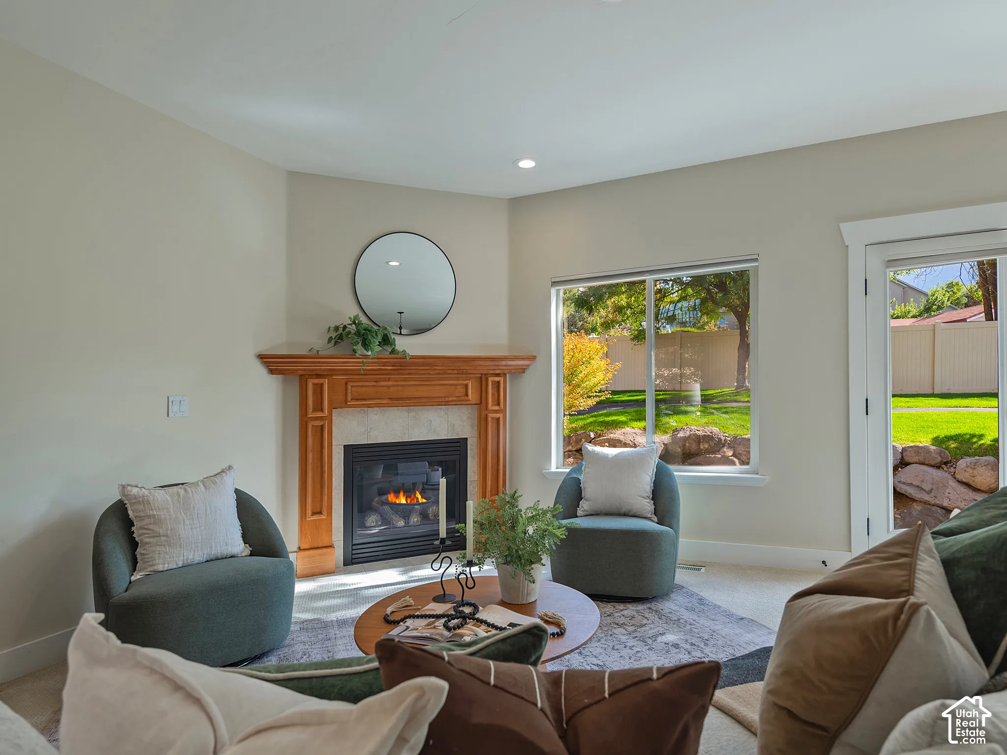 Fireplace with wood mantel and tile surround, recessed lighting, large window overlooking yard, exterior door with glass panel