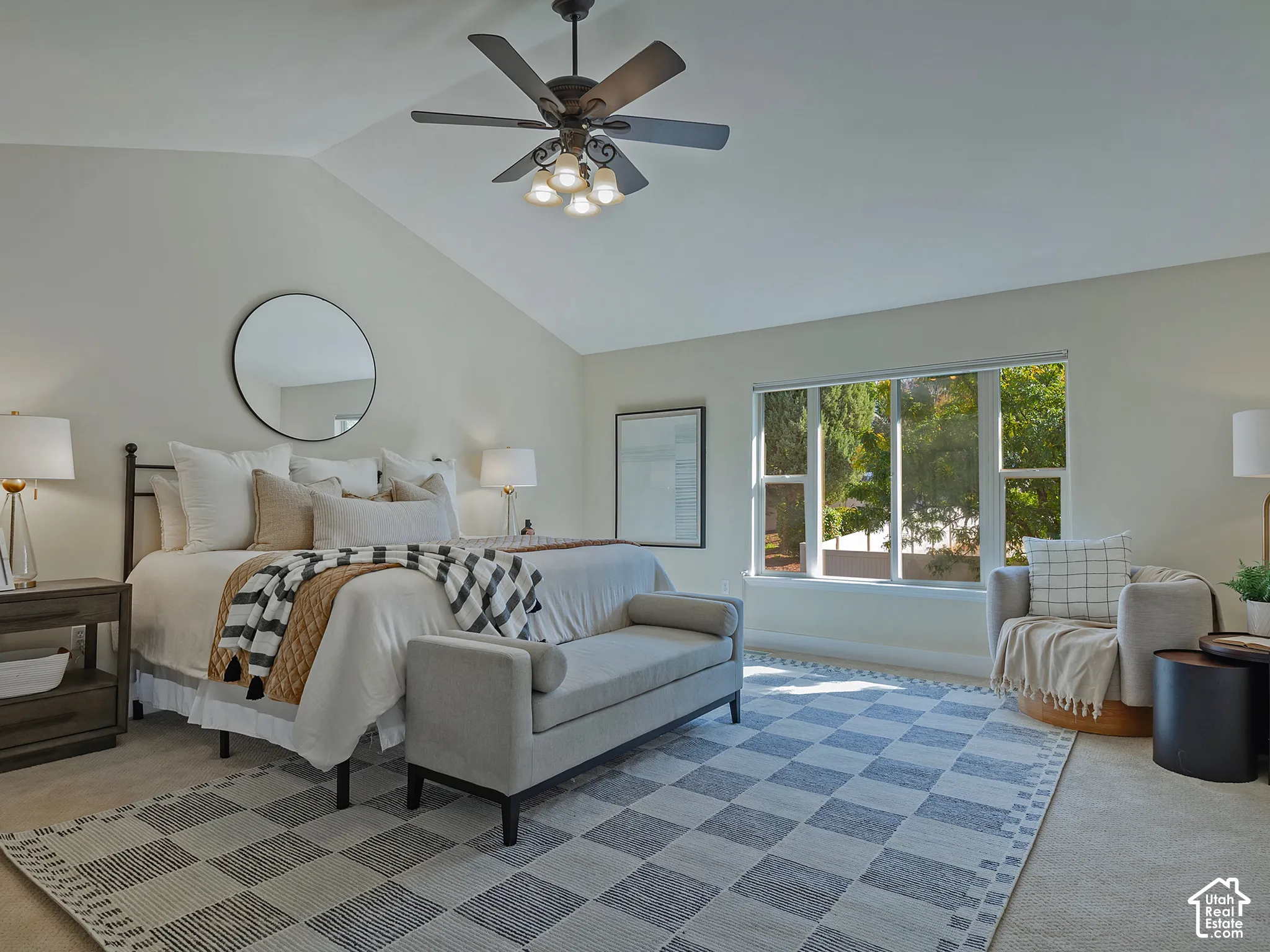 Vaulted ceiling with a ceiling fan, large window with ample natural light, and carpeted flooring