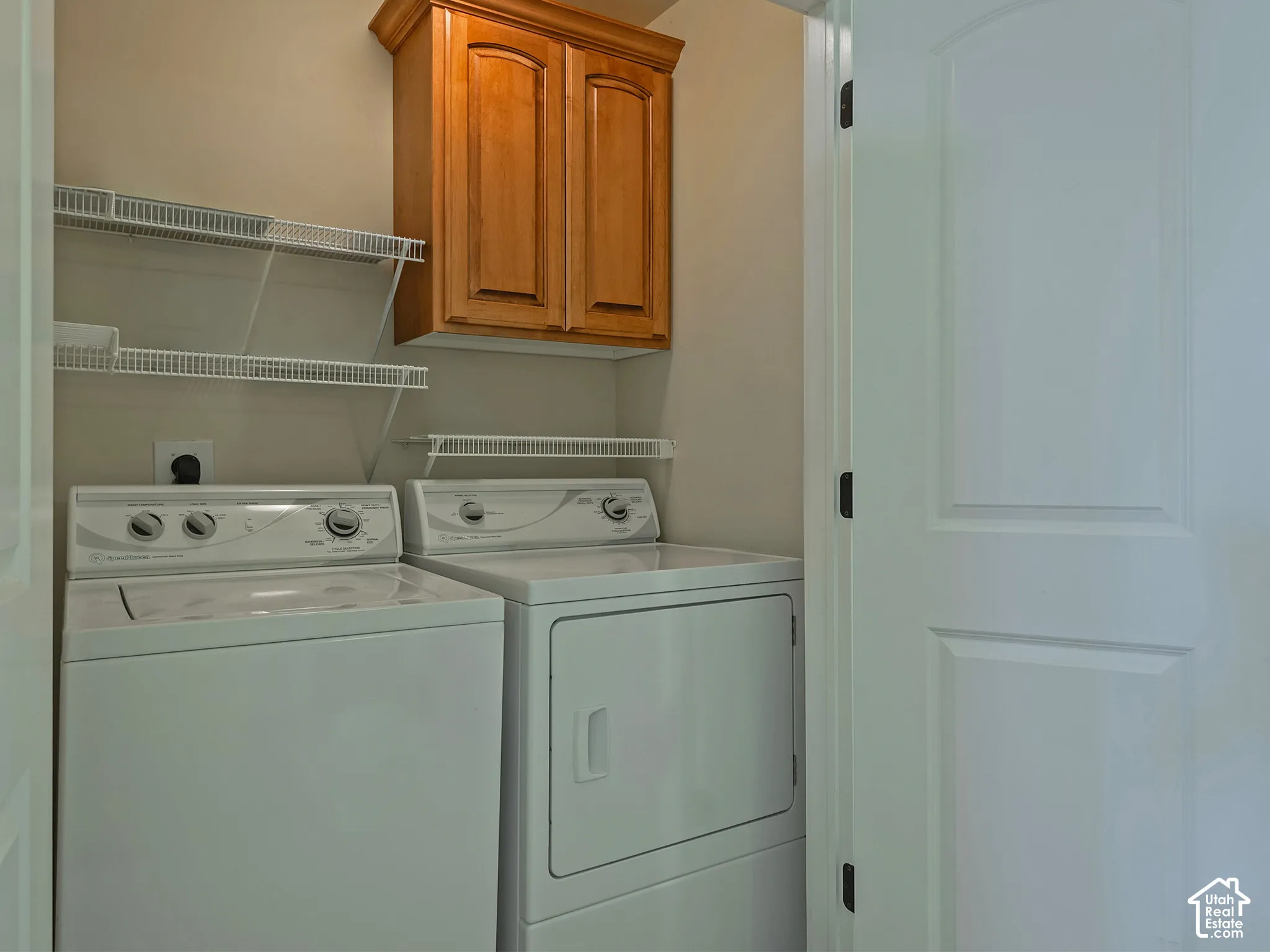 Laundry area featuring overhead wood-finish cabinetry, white wire shelving, and neutral wall paint