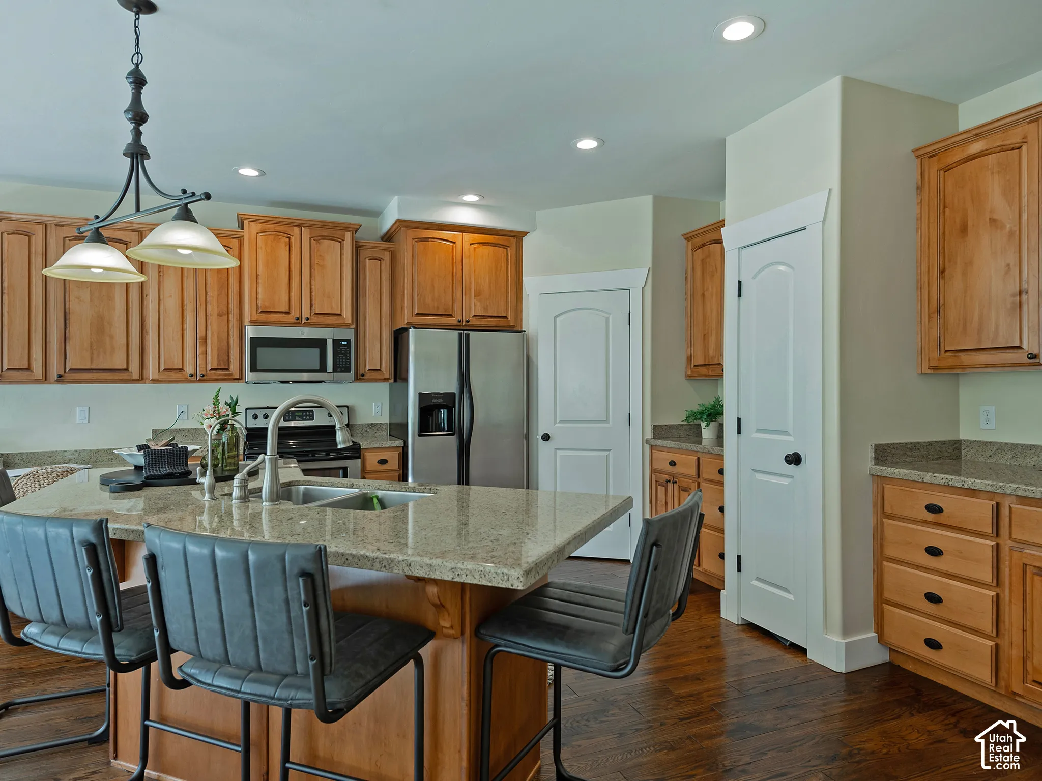 Kitchen featuring wood-finish flooring, light wood cabinetry, stainless steel appliances, a large central island with seating, and recessed lighting