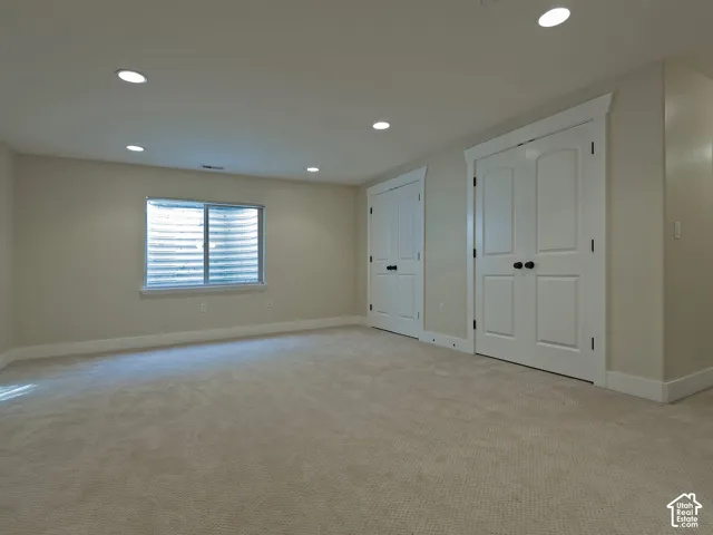 Recessed lighting illuminating neutral-toned walls and plush carpeting