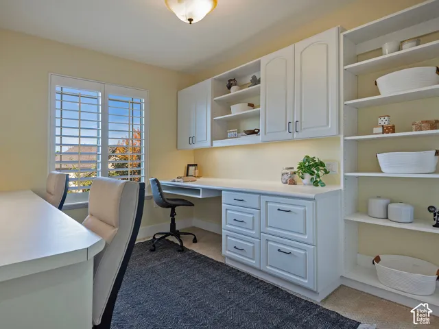 Built-in desks, extensive white cabinetry, and open shelving provide comprehensive storage and workspace