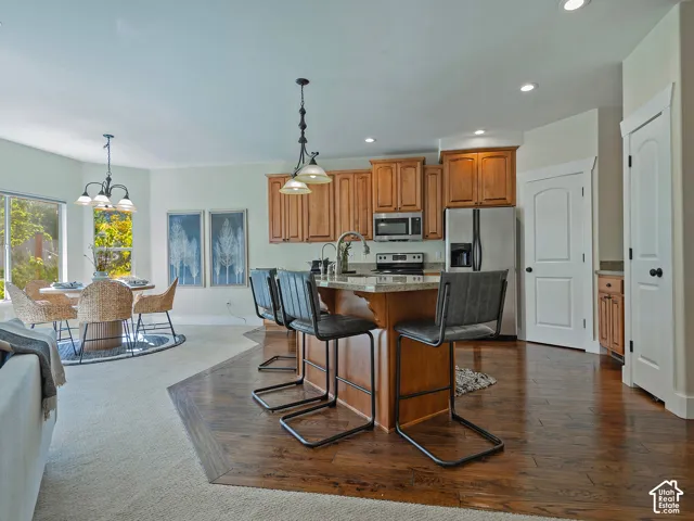 Kitchen featuring wood-finish cabinetry, stainless steel appliances, and a central island with a sink