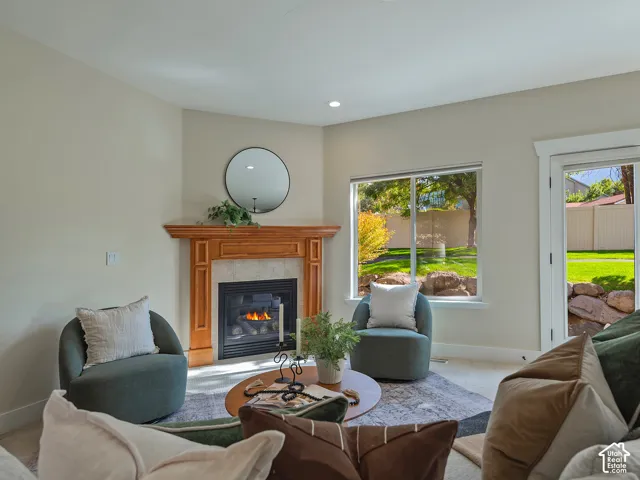 Fireplace with wood mantel and tile surround, recessed lighting, large window overlooking yard, exterior door with glass panel