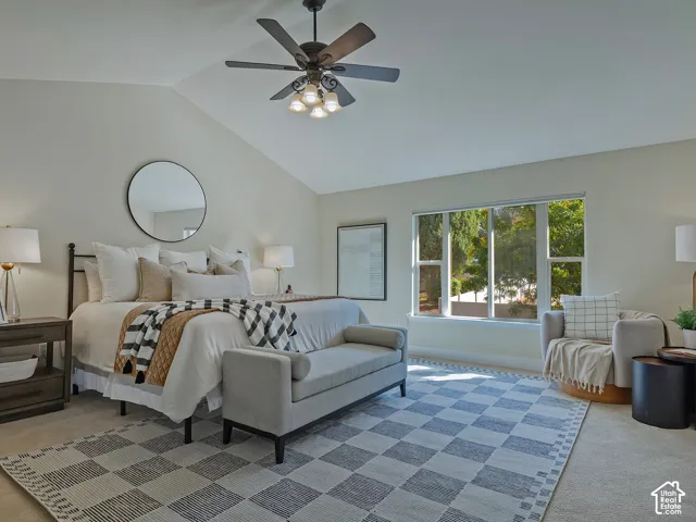 Vaulted ceiling with a ceiling fan, large window with ample natural light, and carpeted flooring