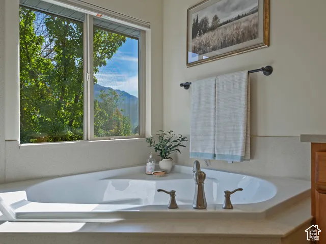 Built-in corner soaking tub with a deck-mounted faucet and neutral-toned surround