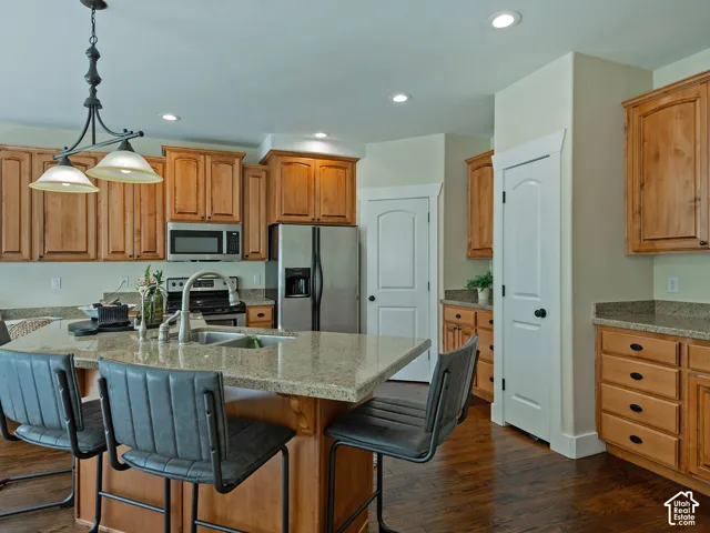 Kitchen featuring wood-finish flooring, light wood cabinetry, stainless steel appliances, a large central island with seating, and recessed lighting