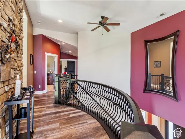 Curved wrought iron railing leading to a spacious hallway with wood-finish flooring