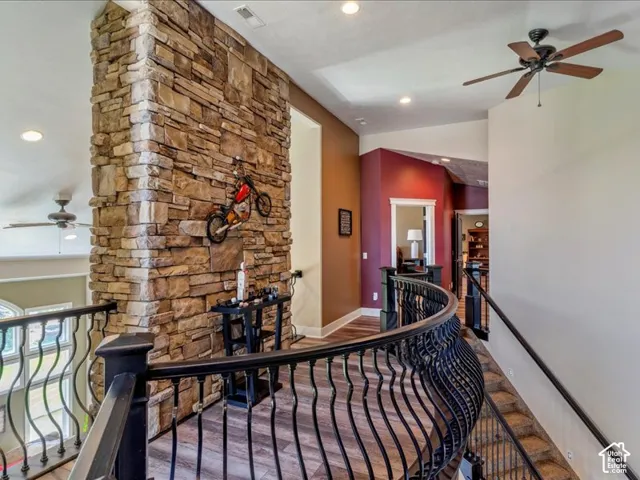 Striking architectural focal point featuring a substantial stacked-stone fireplace with decorative metalwork, anchoring a multi-level hallway
