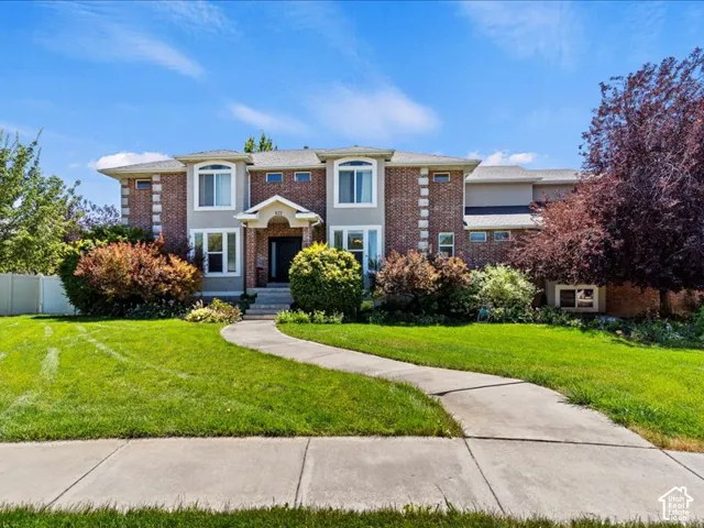 Brick and siding exterior with multiple windows, mature landscaping, and a curved concrete walkway