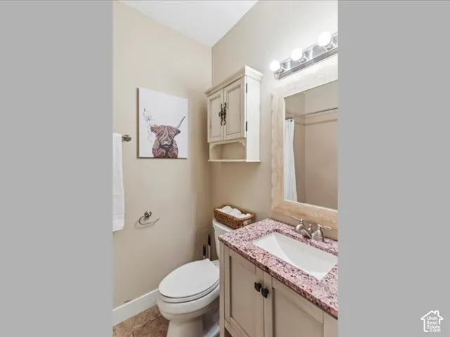 Vanity with a pink speckled countertop and undermount sink, a framed mirror, and a wall-mounted light fixture