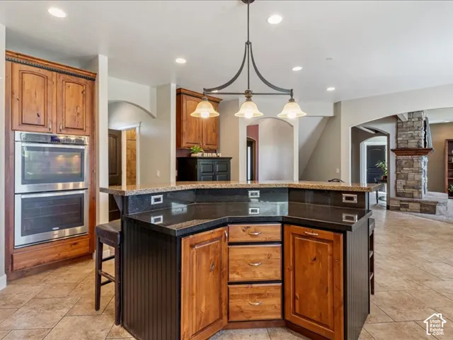 Spacious kitchen island with dark stone countertops, integrated electrical outlets, and wood cabinetry