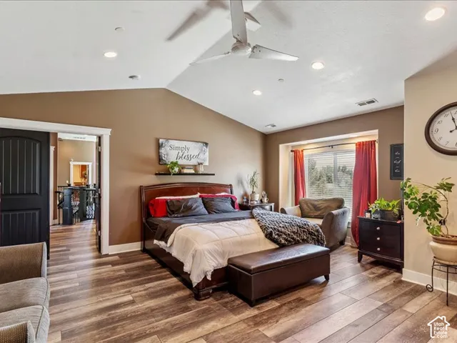 Wood-finish flooring, vaulted ceiling, recessed lighting, and a bay window