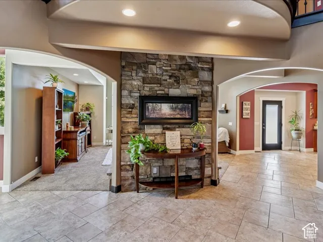 Stone accent wall with recessed lighting, tile flooring, and arched doorways