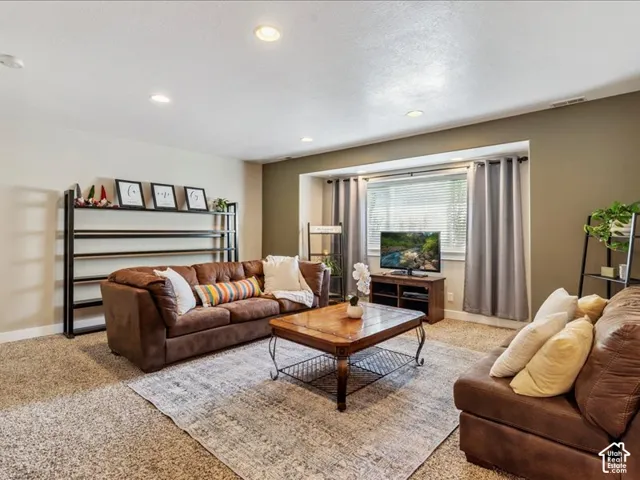 Recessed lighting illuminates this living space with textured carpet flooring