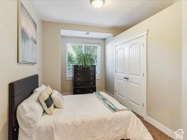 Recessed window with natural light, textured carpet flooring, white trim details, and white paneled bi-fold doors