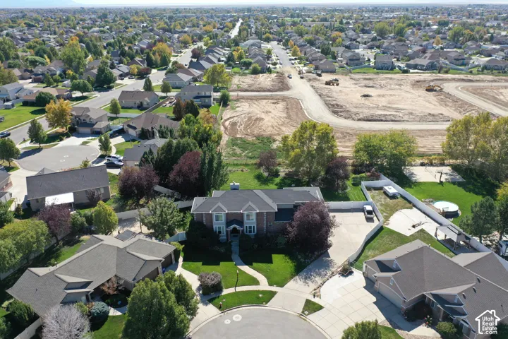 Residential property featuring a brick facade with white trim, dark shingle roof, and an expansive paved driveway