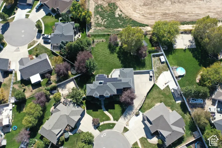 Expansive lot featuring mature trees, a manicured lawn, and a paved sport court