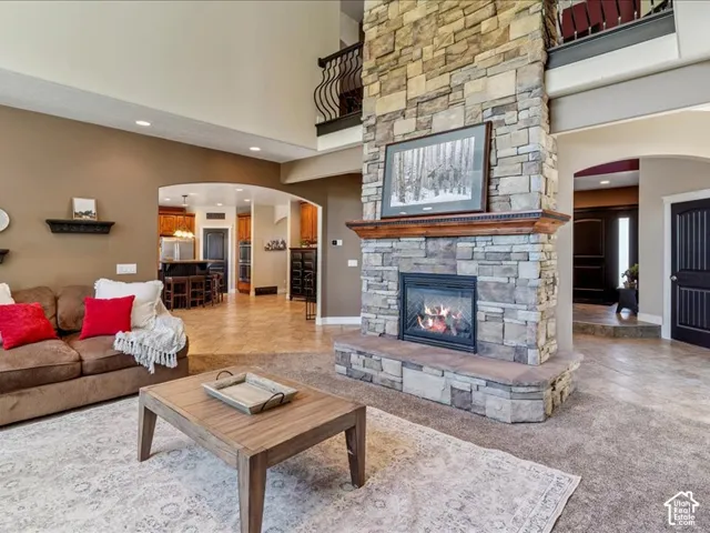 Two-story stone-clad fireplace with wood mantel, vaulted ceilings, arched doorways, a second-story balcony with wrought iron railing, and recessed lighting