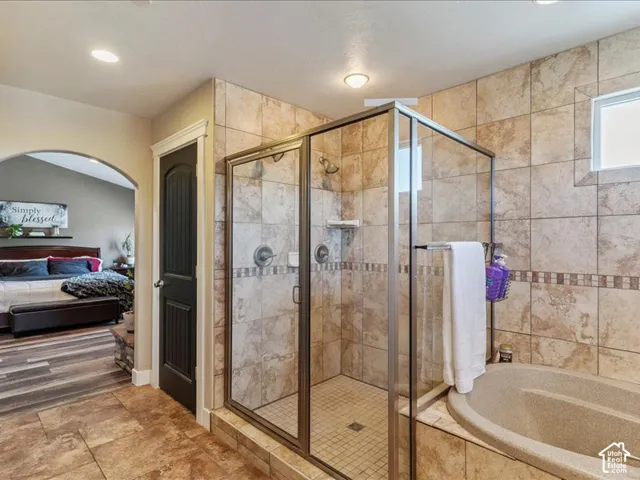 Tile flooring, glass-enclosed shower, built-in soaking tub, tiled shower walls, and a transom window