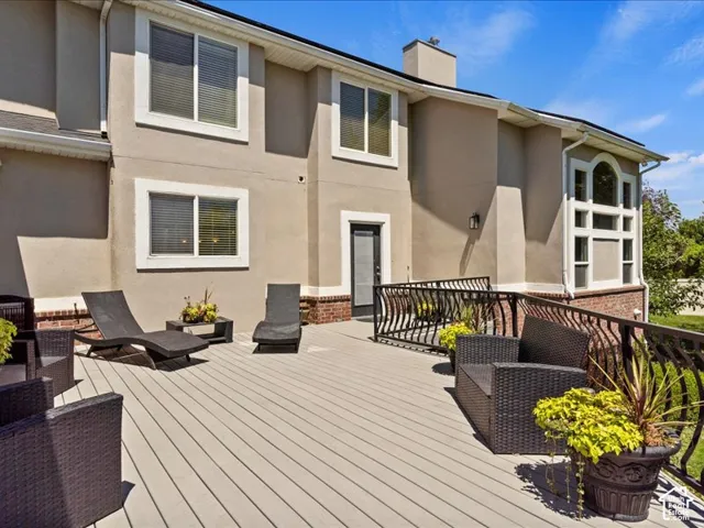 Spacious composite deck with ornate black railings, stucco exterior, multiple windows, and a prominent arched window feature