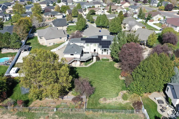 Expansive backyard with a manicured lawn, mature trees, multi-level decking, and solar panels