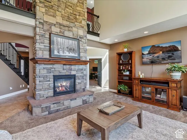 Two-story stone fireplace with wood mantel, recessed lighting, and an open balcony overlooking the living space