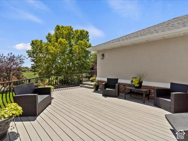 Expansive deck with slatted flooring, decorative metal railing, and exterior wall with brick detailing
