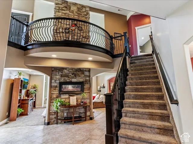 Two-story entryway featuring tile flooring, a carpeted staircase with dark wood and wrought iron railings, and a stone accent wall