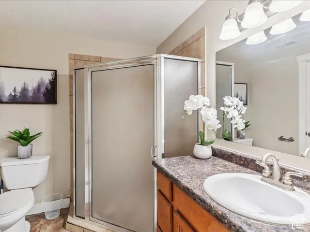 Bathroom featuring a wood-finish vanity with an integrated oval sink, a shower enclosure with frosted glass, and tiled shower surround