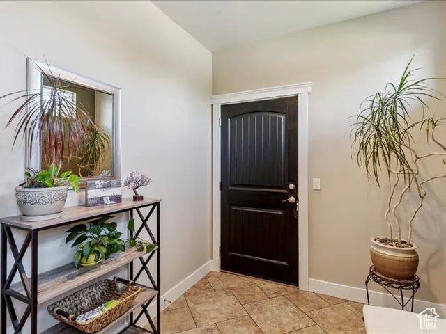 Entryway with tile flooring, a dark wood-paneled door, and white trim