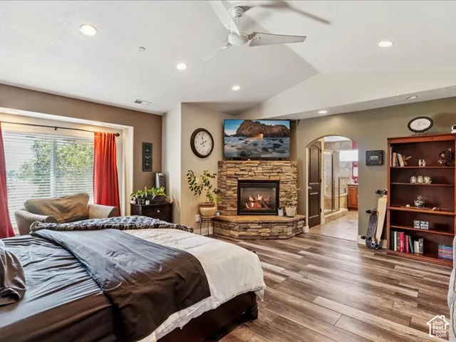 Stone-surround fireplace, wood-finish flooring, recessed lighting, ceiling fan, and arched doorway