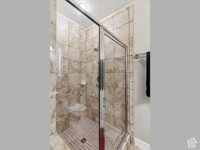 Glass-enclosed shower featuring natural-tone tile walls and floor, built-in soap dish, and a shower head