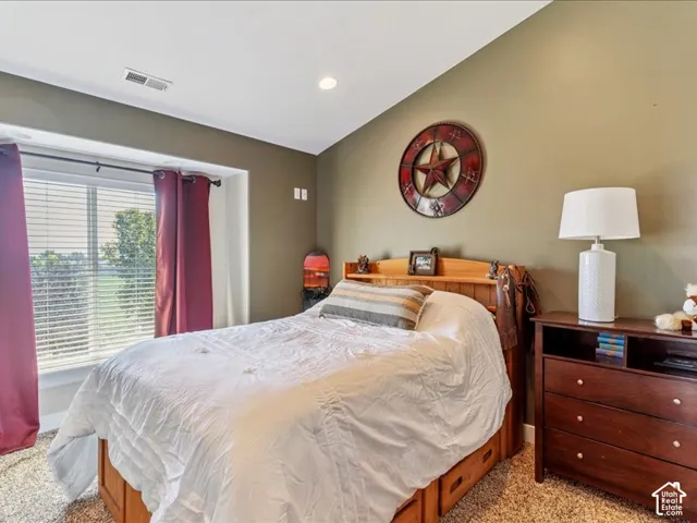 Recessed ceiling lighting, window with blinds, wood-finish bed frame with built-in drawers, dark wood-finish dresser