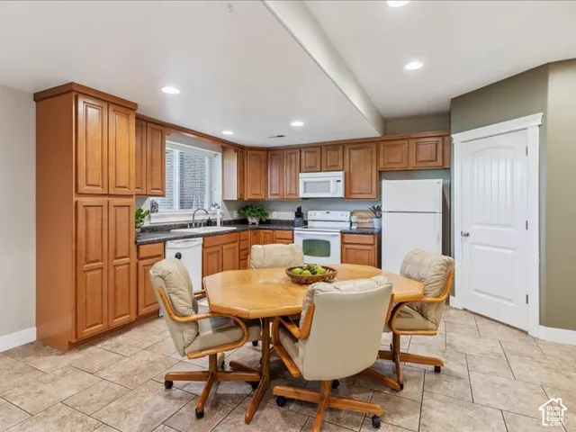 Kitchen with wood cabinetry, dark countertops, a window over the sink, recessed lighting, and tile flooring