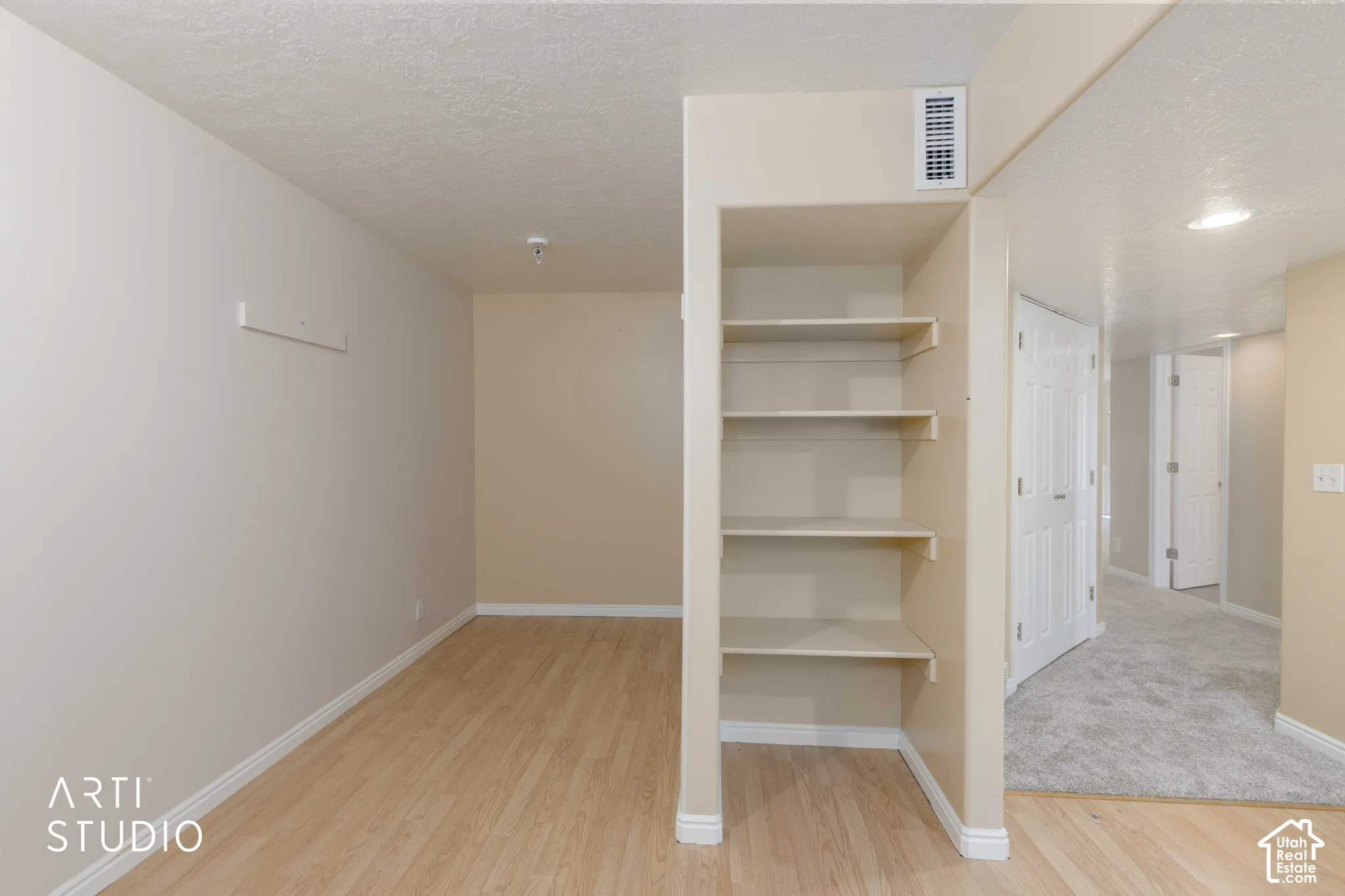 Wood-finish flooring, built-in shelving, white trim, and a textured ceiling