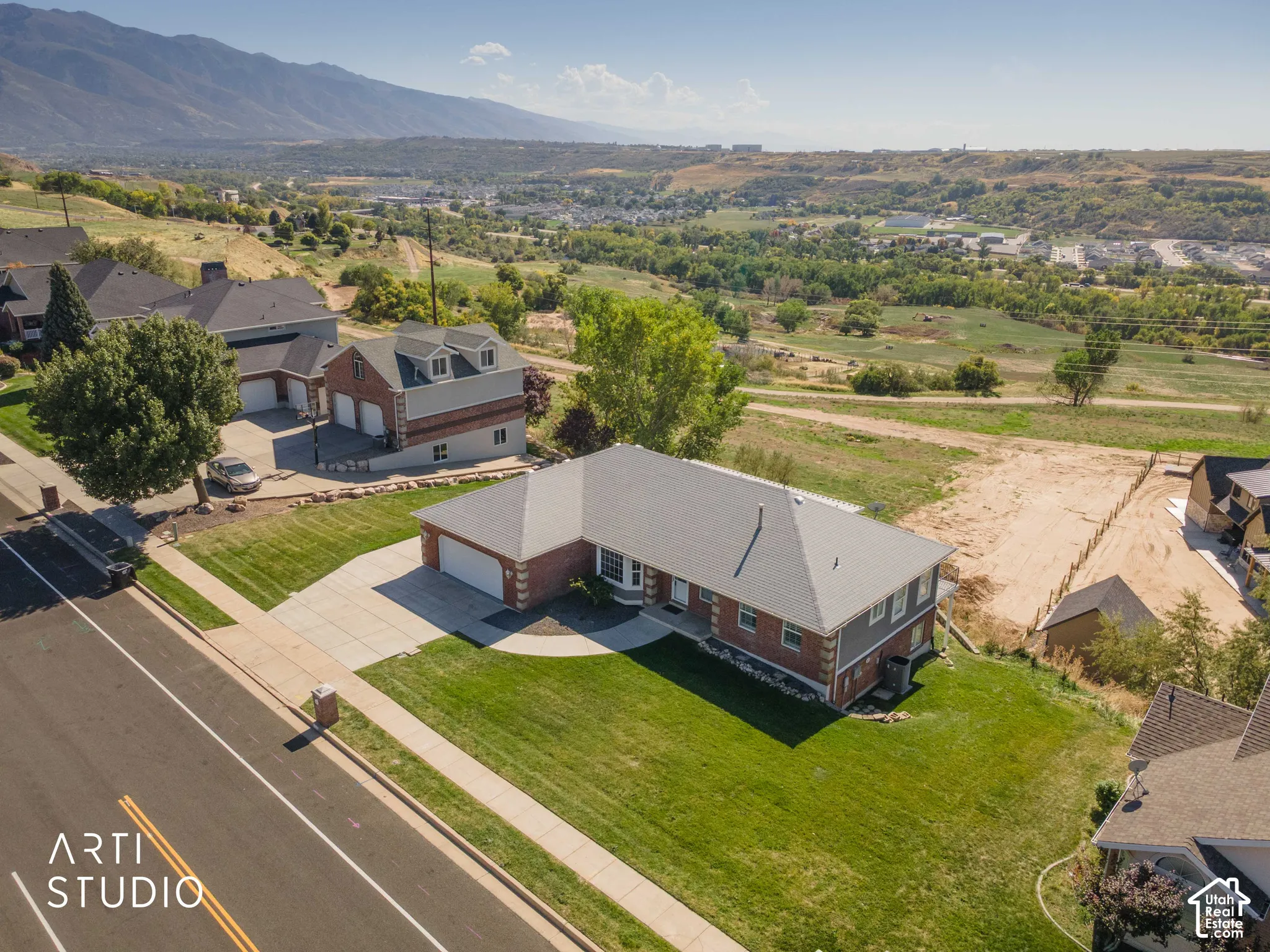 Traditional brick and siding exterior with a multi-car driveway, attached garage, and mature landscaping