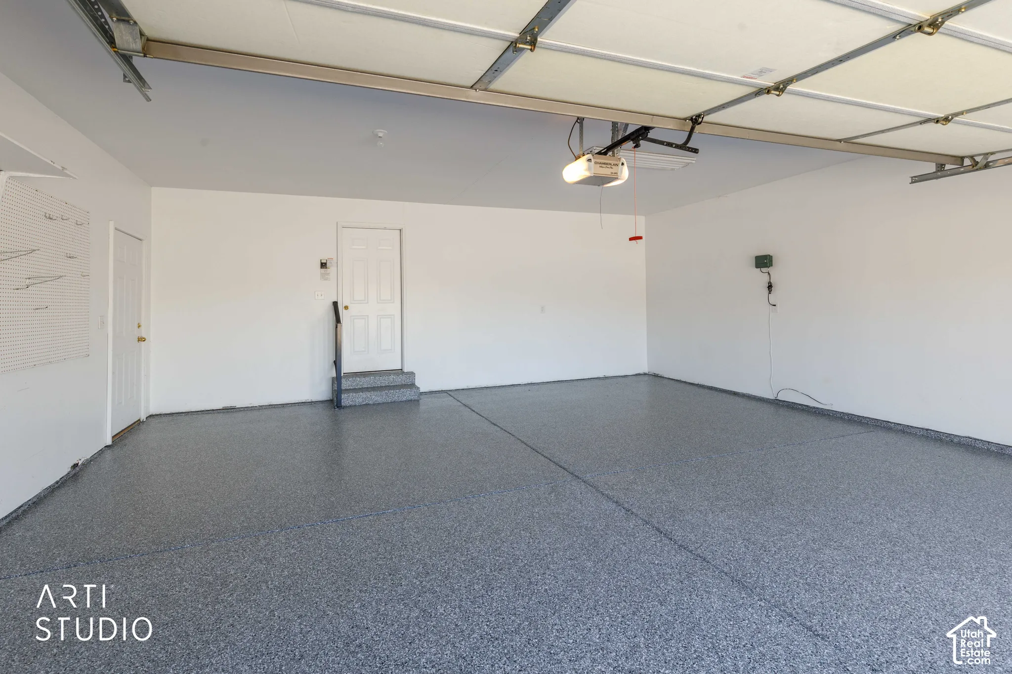 Spacious garage featuring a durable speckled epoxy floor, white painted walls, and an automatic garage door opener