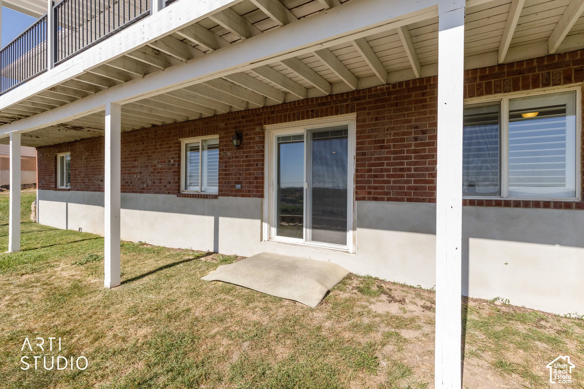 Brick exterior with white trim, patio door, white-framed windows, and covered outdoor space