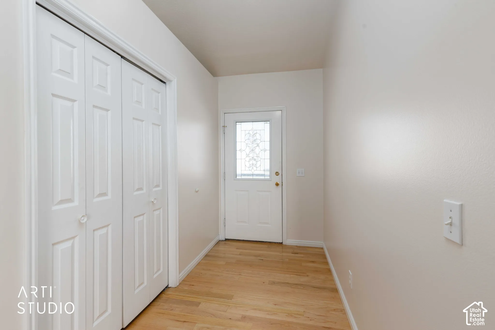 Entryway featuring wood-finish flooring, a decorative glass paneled door, and bi-fold closet doors
