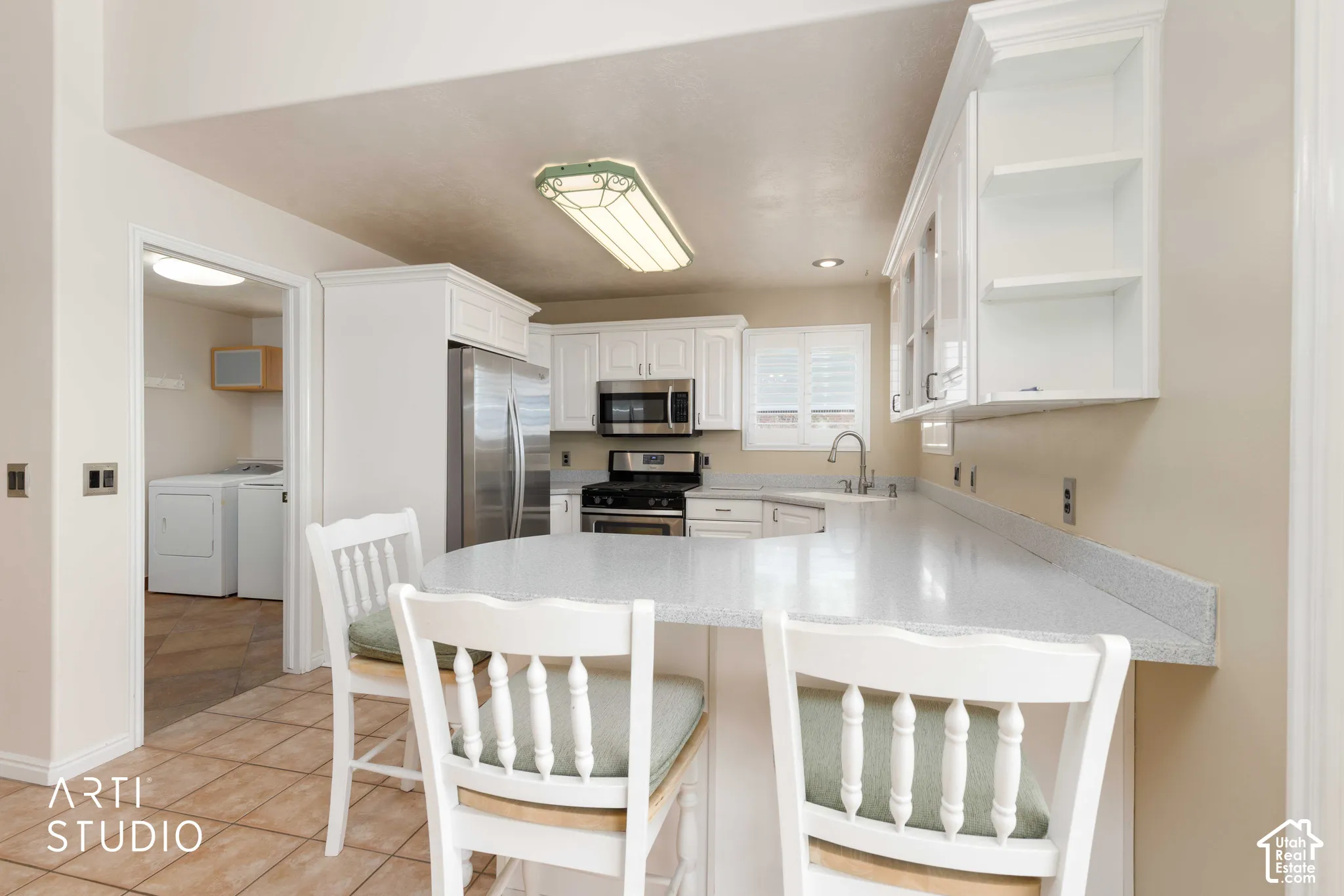 Kitchen featuring white cabinetry, stainless steel appliances, a breakfast bar, and tile flooring