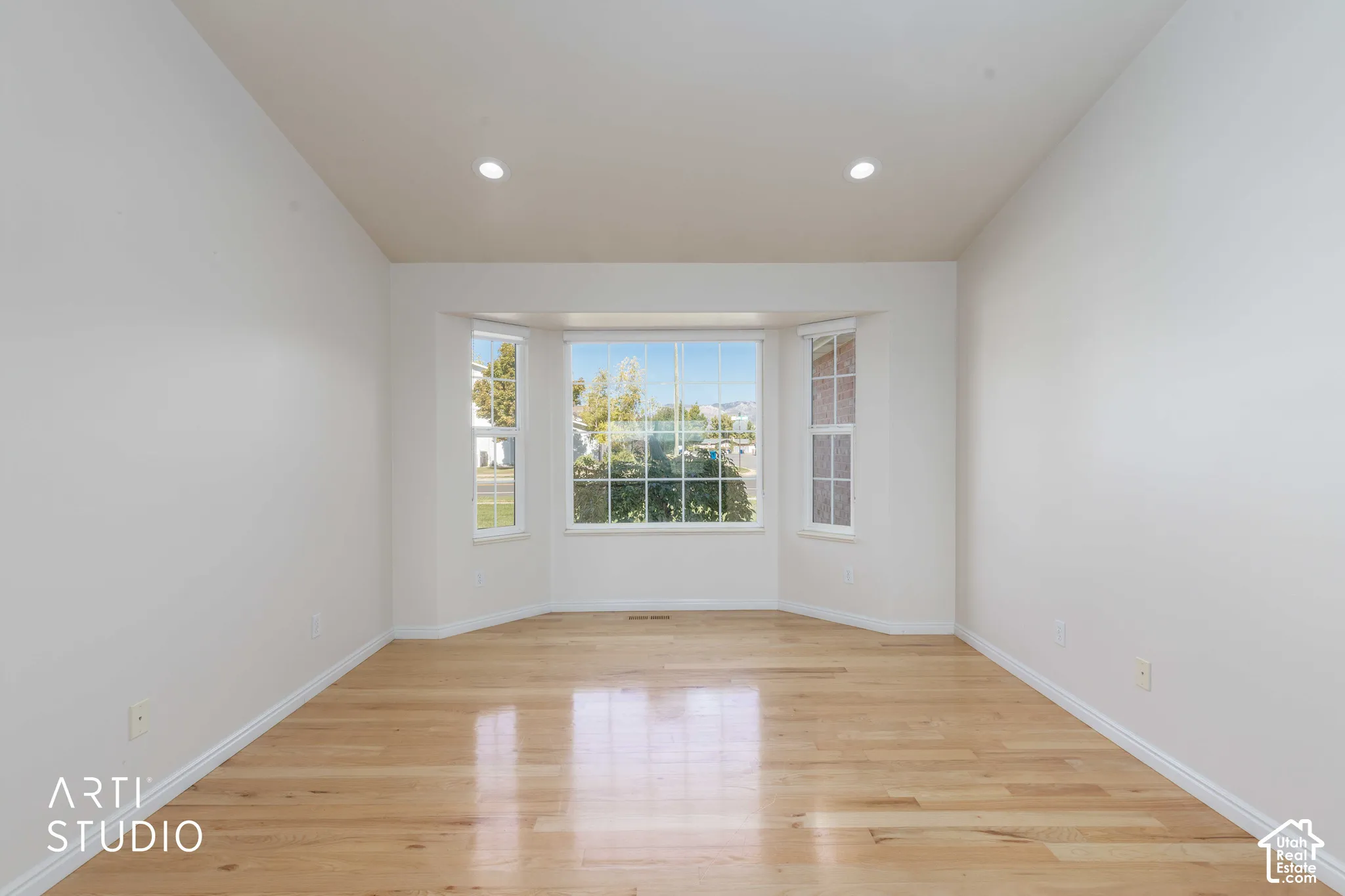 Bay window with multiple panes, recessed lighting, wood-finish flooring, and white painted walls