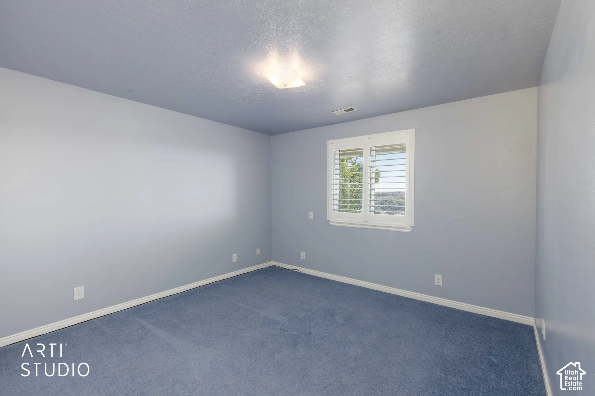 Window featuring white louvered shutters, flush mount ceiling light fixture, and wall-to-wall carpeting