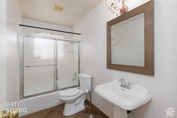 Wall-mounted pedestal sink, chrome-finish faucet, framed mirror, and a tub with sliding frosted glass doors